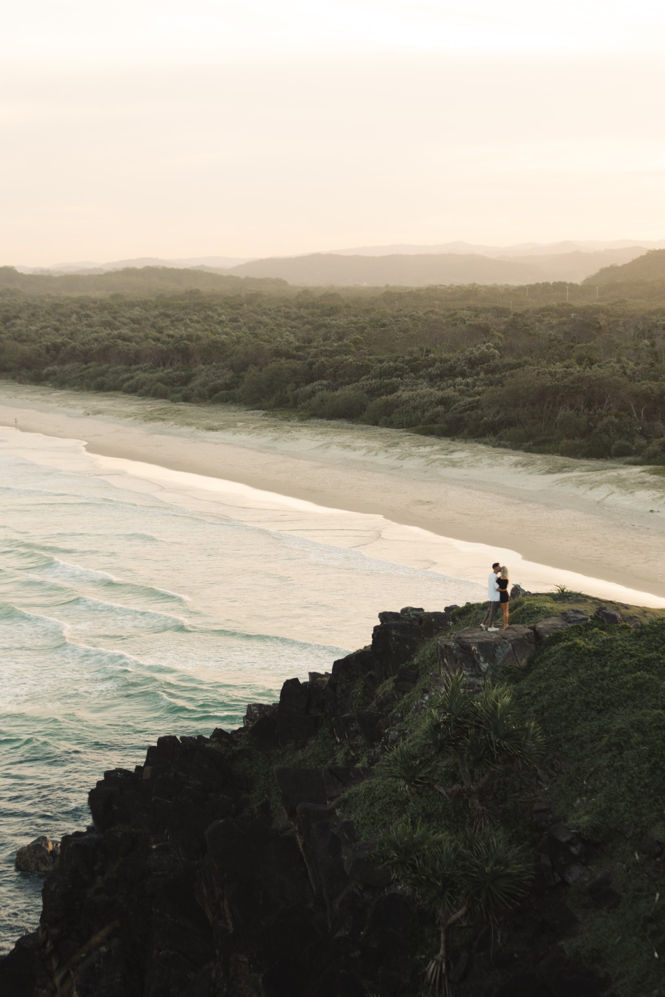 Sarah and Alex on a headland above the sea at sunset